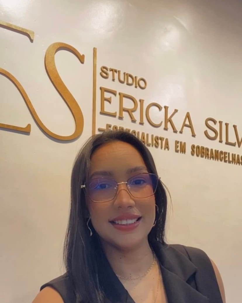 Ericka Silva sorrindo diante do letreiro dourado do Studio Ericka Silva Beauty